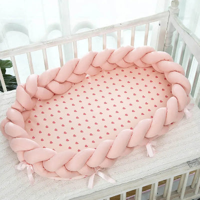 Rducteur de lit bebe : cocon tressĂ© rose dans un berceau, posĂ© sur un matelas Ă cĆurs rouges. Ambiance douce et sĂ©curisante pour le sommeil de bĂ©bĂ©.