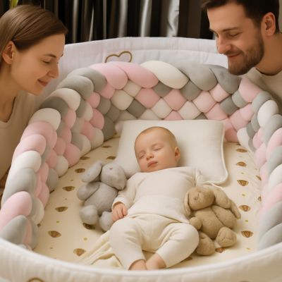 bĂ©bĂ© de 6 mois endormi dans berceau blanc, entourĂ© de peluches et dâun tour de lit tressĂ© rose, gris et blanc. Ses parents le regardent avec tendresse depuis lâextĂ©rieur du lit.