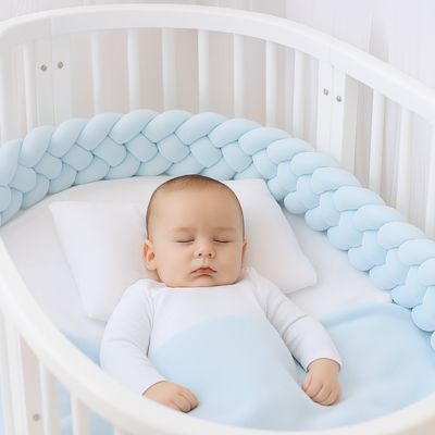 Tresse de lit bébé : bébé de 6 mois endormi au centre d’un berceau blanc, tresse bleu ciel, oreiller moelleux et couverture douce. Sécurité et confort réunis.