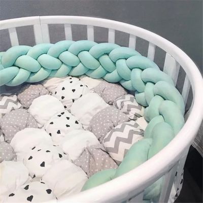 Tresse de lit bébé : berceau rond avec tresse vert pistache moelleuse, matelas patchwork à motifs cœurs, pois et chevrons. Confort et style pour chambre bébé.
