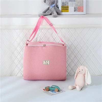Sac rose posé prÚs de jouets doux dans une chambre enfantine, ambiance soignée et chaleureuse autour du cocon pour bebe