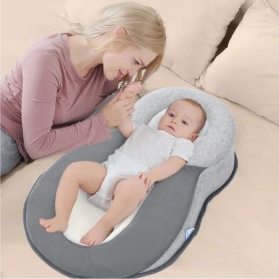 Bébé reposant dans un cocon pour bebe ergonomique sur un lit, accompagné de sa maman dans une ambiance douce et sécurisante.