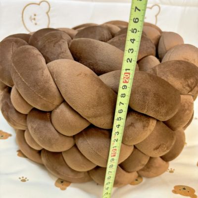 Tour de lit tressé : tresse brun épaisse et moelleuse mesurée à 20 cm de hauteur, posée sur fond blanc à motifs pattes et visages d’oursons. Confort et sécurité pour bébé.