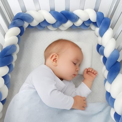 Tresse de lit bébé : bébé endormi dans un berceau blanc avec tresse bleu et blanche, drap à pois, oreiller moelleux et couverture douce. Confort et sécurité assurés.