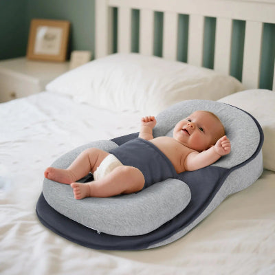 Bébé allongé dans un cocon pour bebe gris sur un lit blanc, reposant paisiblement dans une chambre douce avec lit et décoration en arrière-plan.