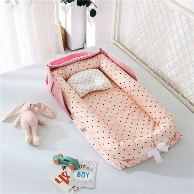 Cocon pour bebe rose à pois avec oreiller intégré, entouré de jouets doux et d’une carte “It’s a boy”, dans une chambre lumineuse et apaisante.