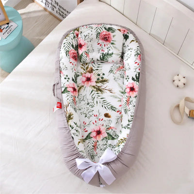 nid pour bebe décoré d’un motif floral des roses roses et rouges avec des feuilles vertes pose sur un lit blanc dans une chambre decore