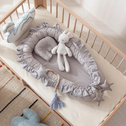 un nid pour bebe couleur gris sur un matelas blanc dans un berceau en bois avec des toutous dans une chambre de bebe