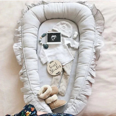 un nid pour bebe gris avec des vêtements pour bebe une photo d'u fétus sur un lit blanc