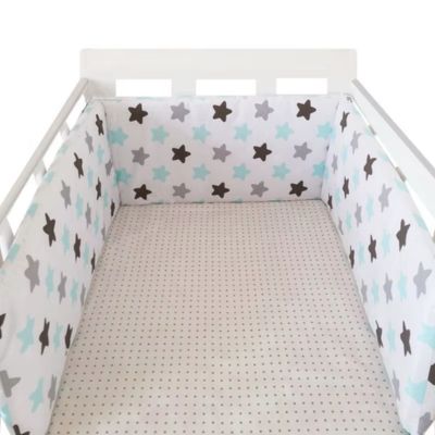 Tour de lit à motifs étoiles gris, noirs et bleus, installé dans un berceau blanc avec drap à pois pour une ambiance douce et sécurisante.