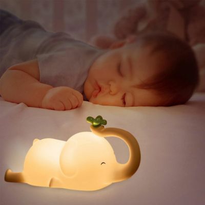 veilleuse éléphant allumé sur lit avec un bébé qui dors paisiblement dans sa chambre