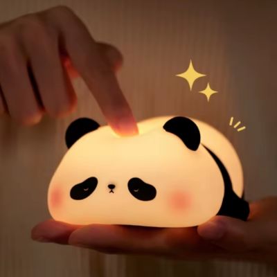 veilleuse panda illuminé sur une main et un doigt qui pèse sur le panda