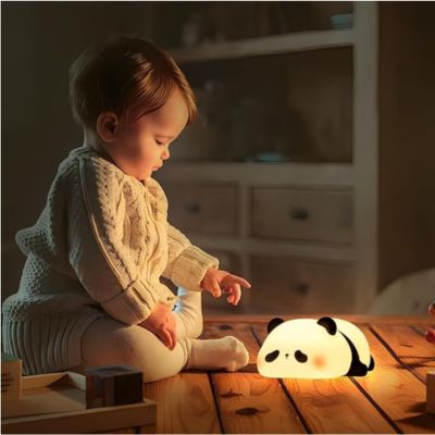 veilleuse panda illuminé sur une table en bois a cote d'un enfant assis sur la table