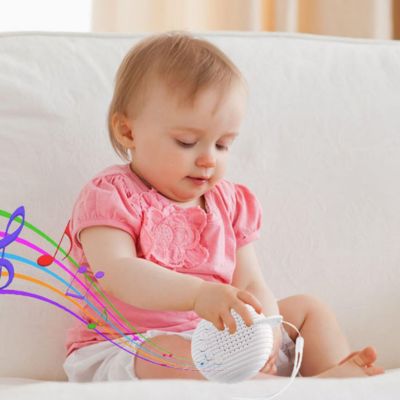 un enfant assis joue avec une veilleuse bruit blanc qui diffuse des sons apaisant.