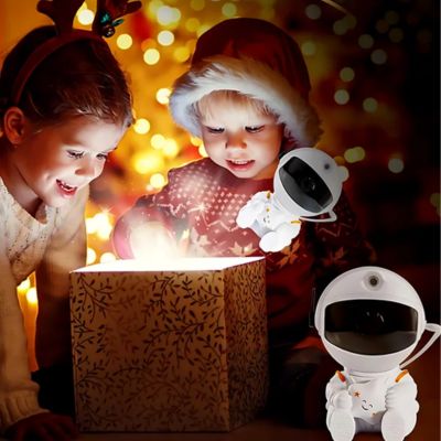 deux petites fille toute heureuse regarde une boite de cadeau illuminé et a cote une villeuse projection astronaute blanc dans une chambre éclairé de petite lumière 